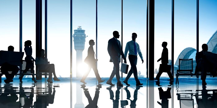 eople in business attire carrying briefcases walking through airport 